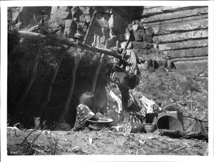 Havasupai Indian woman, Chick-a-pan-a-gie's wife, parching corn in a basket in front of her "Hawa" or dwelling, 1898