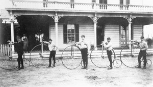 Portrait of 5 riders of the Los Angeles Bicycle club with their high wheeler machines, in front of Agriculture Park Roadhouse, ca.1887