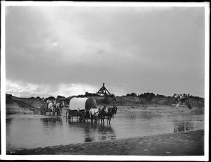 Two covered wagons fording the little Colorado River beside a cable ferry, 1903