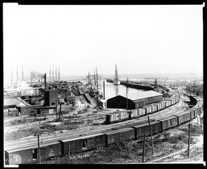 View of Los Angeles (San Pedro) Harbor, showing ships unloading along a wharf, 1910-1929