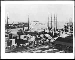 View of the San Pedro Harbor, showing Dead Man's Island and stacks upon stacks of lumber, ca.1900