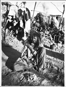 Old blind Chemehuevi Indian woman sitting on the ground, ca.1900