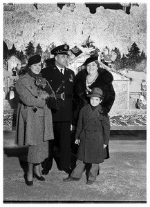 Four people in winter wear posing before a Christmas display