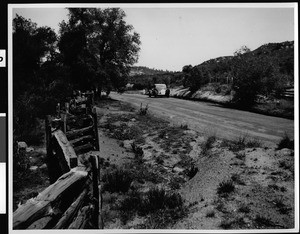 Road in Cuyamaca Park in San Diego County, showing a fence and parked automobile, ca.1932