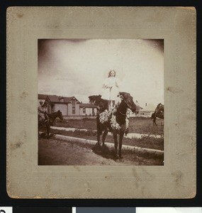 Woman standing horseback during a La Fiesta de Los Angeles celebration, ca.1906