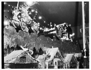 A group of people in Christmas costumes sitting in a display featuring a sleigh pulled by artificial reindeer