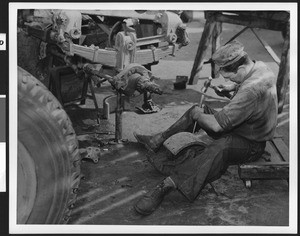 Close-up of a man chiseling something inside an unidentified factory, ca.1940