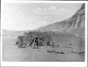 Navajo family at their hogan in Blue Canyon, showing a horse near the entrance, ca.1900