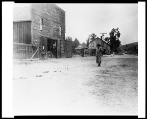 Woman standing in the street in front of the Southern Hotel in Newhall, 1910