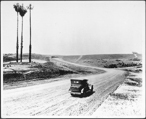 Automobile driving down Sunset Boulevard during the road's construction, ca.1925