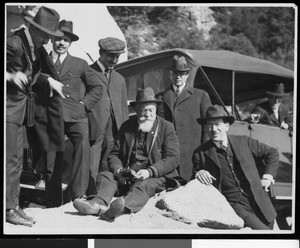 Men on a rock near an early automobile