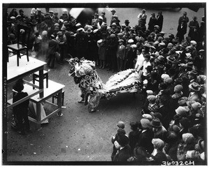 Crowds gathered around a man dressed as a dragon during the Chinese New Year Celebration, Chinatown, 1920-1929