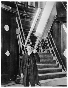 Interior view of Echo Mountain Observatory (Mt. Lowe Observatory?), showing Professor Larkin with his hand on the telescope