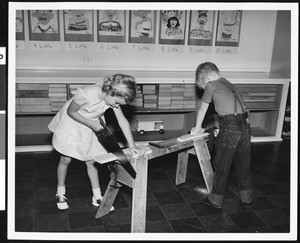 A young girl and boy practicing carpentry in a schoolroom, ca.1940