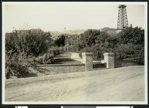 Walkway on Ranch Montebello with oil derricks in the background, ca.1930