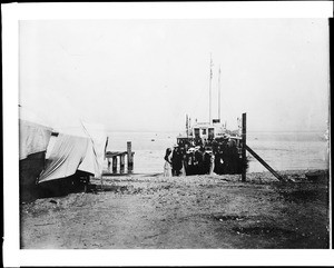 People standing on the shore near a glass bottom boat on Catalina Island