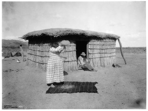 Pima Indian woman winnowing beans over her head onto a mat on the ground, Gila River Reservation