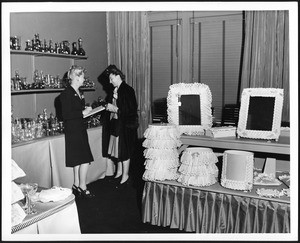 Two women in what looks like a store display room full of knick-knacks, ca.1960-1969