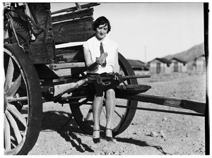 Woman sitting on a wagon while holding guns