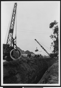 Oil industry construction, showing a worker hanging on a cane, ca.1930