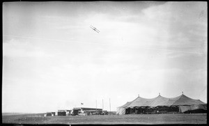 Aviator Philip Orin Parmelee flying over the hangars and field at the Dominguez Hills Air Meet, 1912