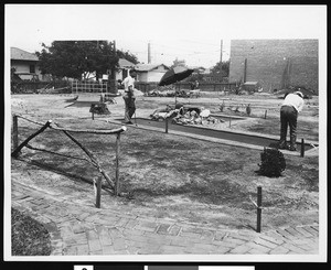 Two people playing on a miniature golf course, ca.1930