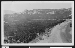 Dirt road leading towards mountains through a valley