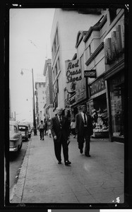 Pedestrians on the sidewalk of the 6300 block of Hollywood Boulevard looking on from Cahuenga Boulevard, 1950-1959