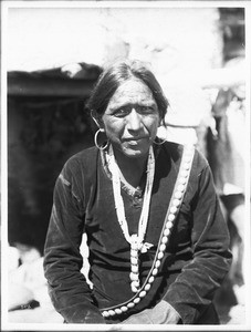 Navajo Indian man wearing large silver earrings, and wampum necklace, ca.1900