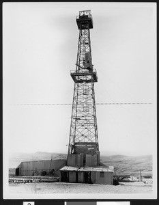 Unidentified oil well, showing low hills in the background, ca.1930