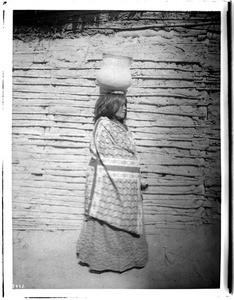 View of a Yuma Indian woman carrying an "olla" on her head, ca.1900