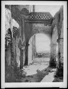 Mission San Luis Rey de Francia, showing a stone grill beyond the dilapidated arcade arches, California, 1900