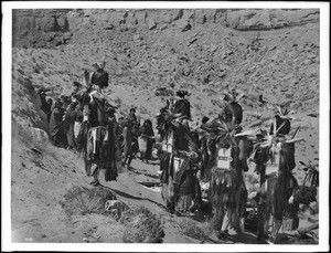 The backs of four costumed dancers (the flute players) during the Hopi Indian flute dance at Oraibi, ca.1901