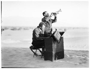 Two men playing the trumpet and piano for a funeral in the desert