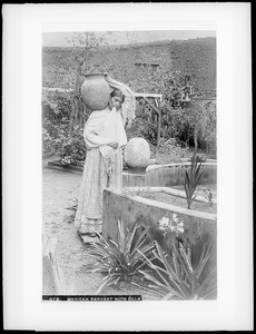 Mexican servant with olla (water jar) on shoulder, ca.1905