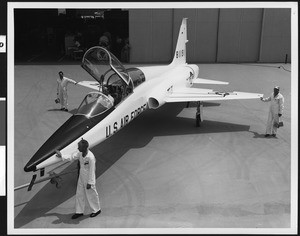 Four men examining a Northrop T-38 outside a hangar, ca.1960