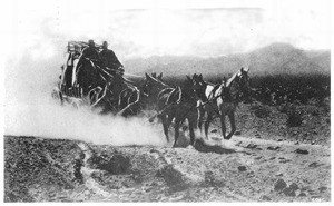 Two men riding on a stage pulled by four horses across the plains, ca.1900