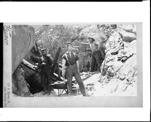 Portrait of three miners standing outside an unidentified mine, 1895-1905