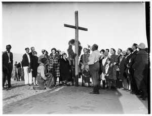 Man pointing at a wooden cross at a funeral in the desert