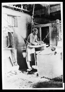 Chinese man working an apparatus with ropes, possibly sifting rice