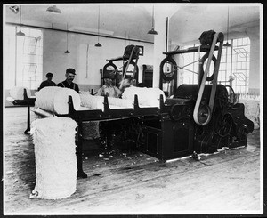 Workers tending to a machine at an unidentified factory