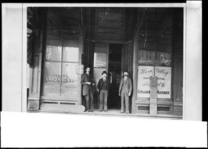 Three men standing outside the entrance to a commercial building in the business district of Bakersfield