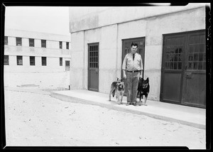 Man standing outside a building holding two dogs