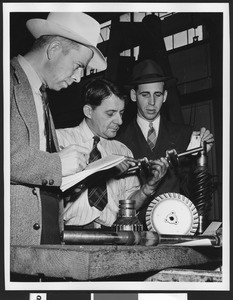Unidentified factory workers inspecting a mechanical part, ca.1950