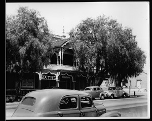 Exterior view of the Elsinor Hotel, showing an automobile in the foreground, ca.1935