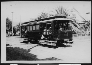 Trolley car moving on an empty road, showing residential houses in the background, ca.1899