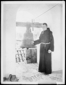 Priest in a tower with the Great Bell (the largest of the bells) in Mission Santa Barbara, 1898