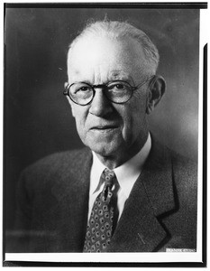 Portrait of an old man wearing a suit and glasses