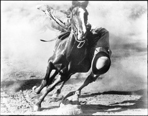 Cowboy grabbing a sack from the ground in mid-gallop, Santa Barbara, ca.1920