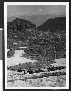 Group of travelers on horseback making their way through snowy foothills